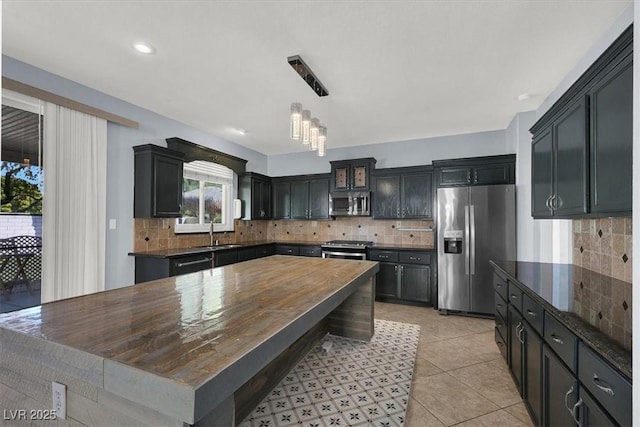 kitchen featuring light tile patterned flooring, sink, pendant lighting, stainless steel appliances, and decorative backsplash