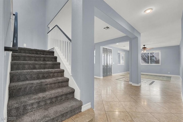 staircase with ceiling fan and tile patterned floors