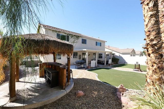 rear view of house with an outdoor bar, a patio area, and a lawn