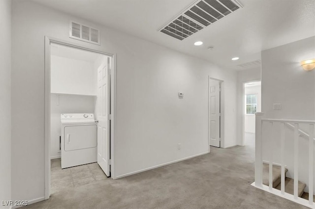 hallway with washer / clothes dryer and light colored carpet