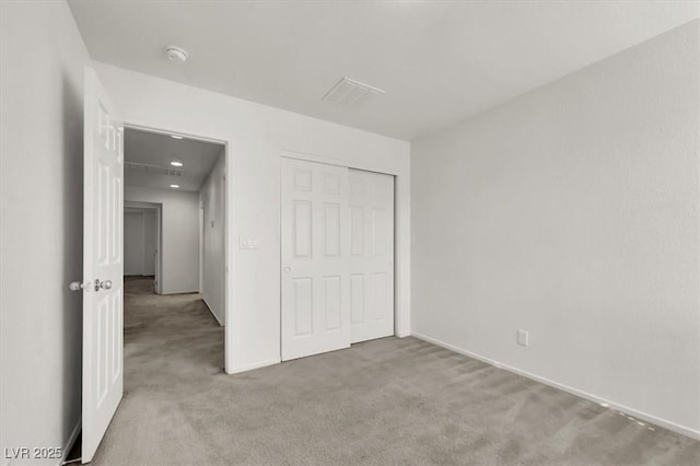 unfurnished bedroom with light carpet and a closet