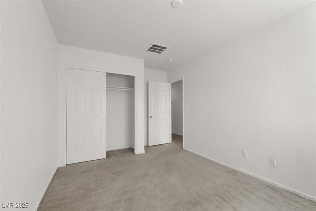 unfurnished bedroom with light colored carpet and a closet