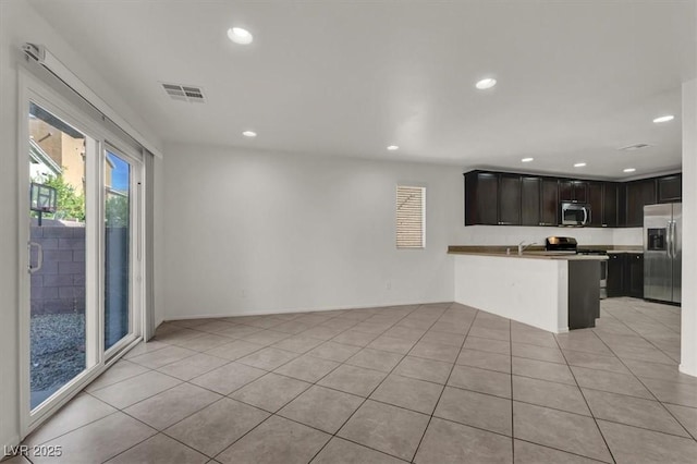 kitchen with a breakfast bar area, dark brown cabinets, light tile patterned floors, appliances with stainless steel finishes, and kitchen peninsula