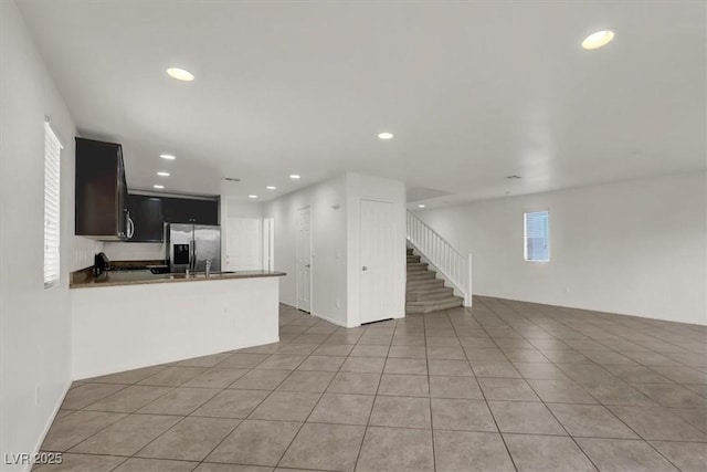 kitchen featuring light tile patterned floors, kitchen peninsula, and stainless steel refrigerator with ice dispenser