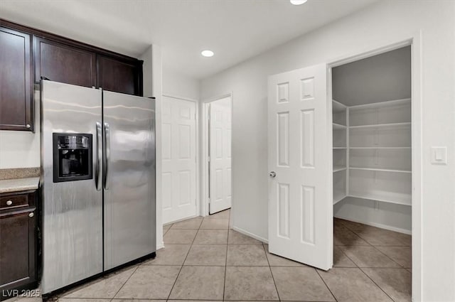 kitchen featuring stainless steel refrigerator with ice dispenser, light tile patterned floors, and dark brown cabinetry