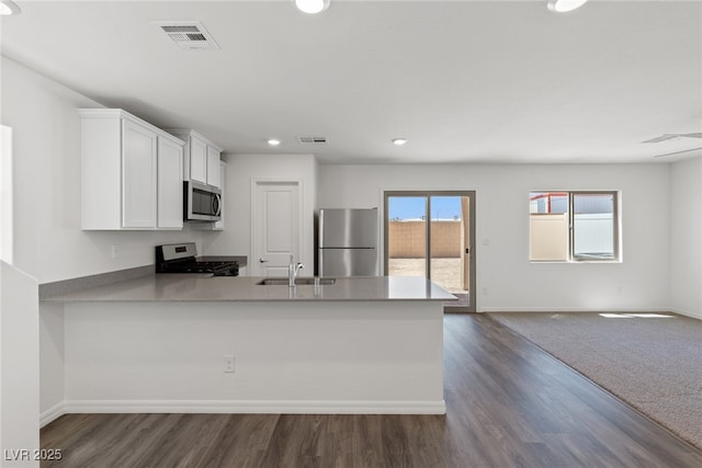 kitchen featuring dark wood-type flooring, sink, kitchen peninsula, stainless steel appliances, and white cabinets