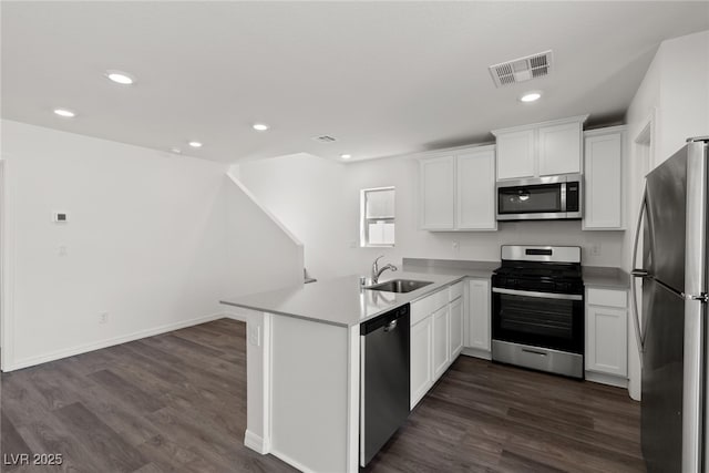 kitchen with sink, white cabinetry, appliances with stainless steel finishes, dark hardwood / wood-style flooring, and kitchen peninsula