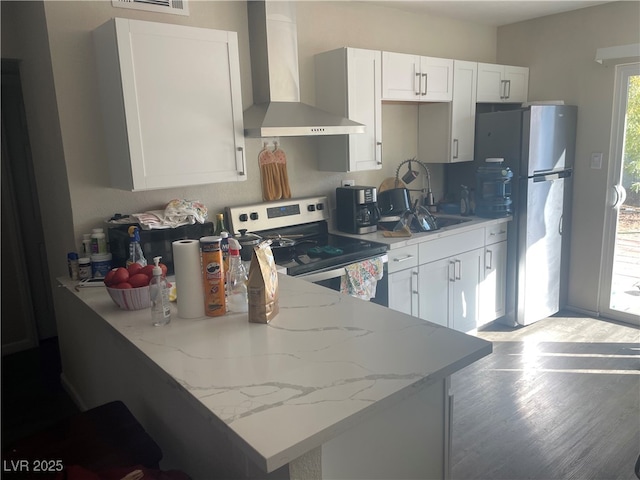 kitchen with white cabinetry, appliances with stainless steel finishes, sink, and wall chimney range hood