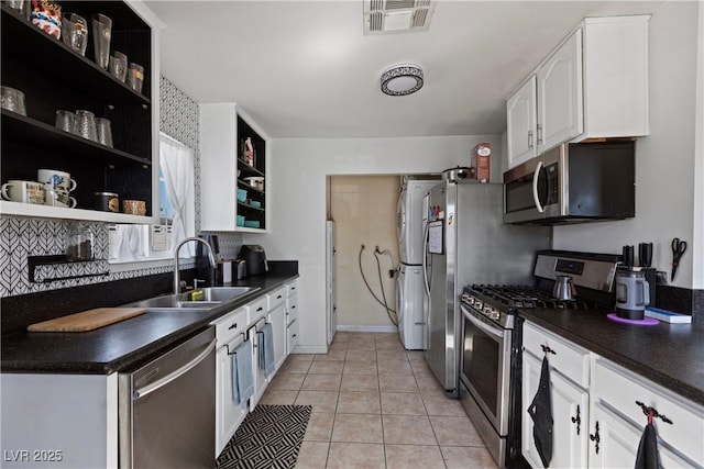 kitchen with appliances with stainless steel finishes, sink, light tile patterned floors, and white cabinets