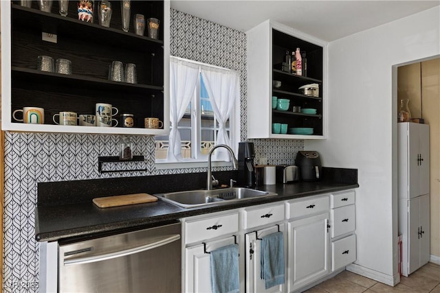 kitchen with light tile patterned flooring, sink, tasteful backsplash, stainless steel dishwasher, and white cabinets