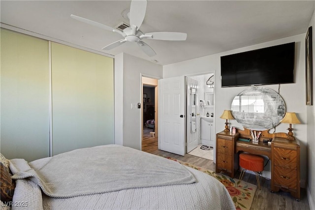 bedroom featuring connected bathroom, wood-type flooring, a closet, and ceiling fan