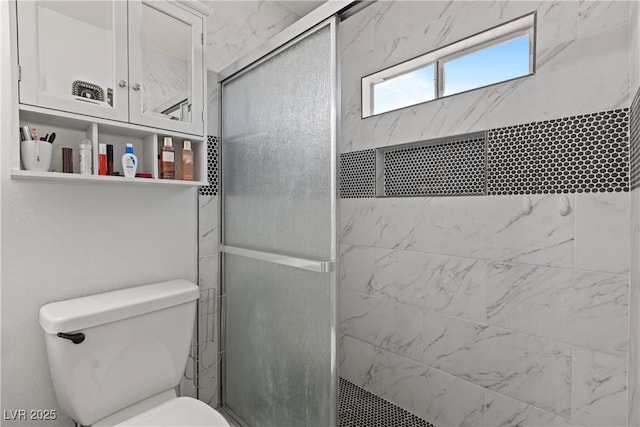 bathroom featuring a shower with door and toilet