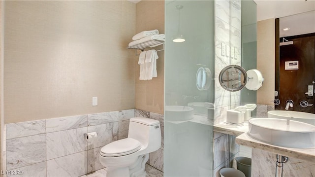 bathroom with sink, tile walls, and toilet