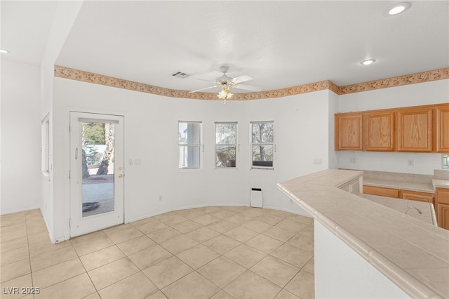 kitchen with light tile patterned flooring, tile counters, and ceiling fan