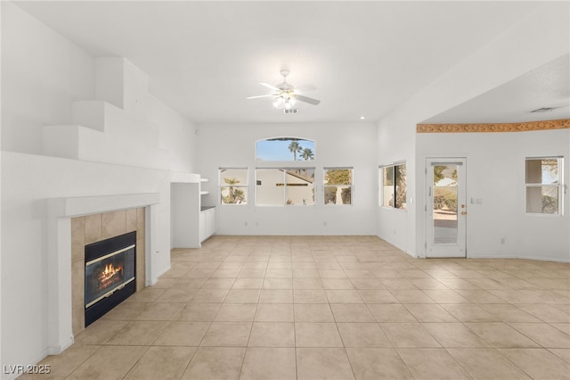 unfurnished living room featuring a tiled fireplace, light tile patterned floors, and ceiling fan