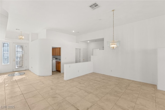 unfurnished living room featuring washer / dryer and a chandelier