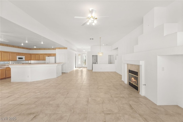 unfurnished living room with a tile fireplace and ceiling fan