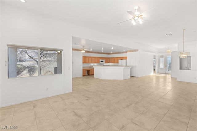 unfurnished living room with ceiling fan with notable chandelier