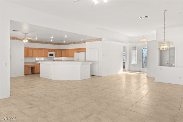 kitchen with pendant lighting, white appliances, ceiling fan with notable chandelier, and a kitchen island