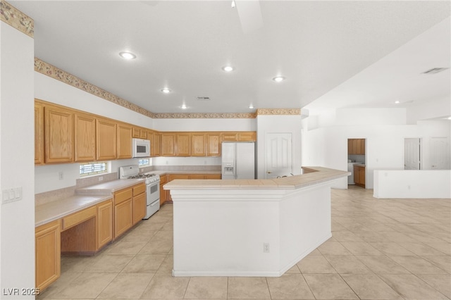 kitchen with washer and dryer, light tile patterned floors, white appliances, and a center island