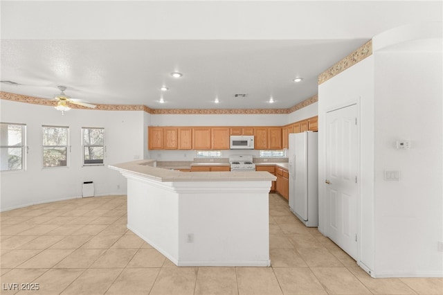 kitchen with light tile patterned floors, white appliances, ceiling fan, and a kitchen island