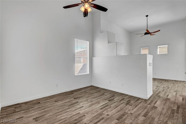 spare room featuring light hardwood / wood-style floors, ceiling fan, and a high ceiling