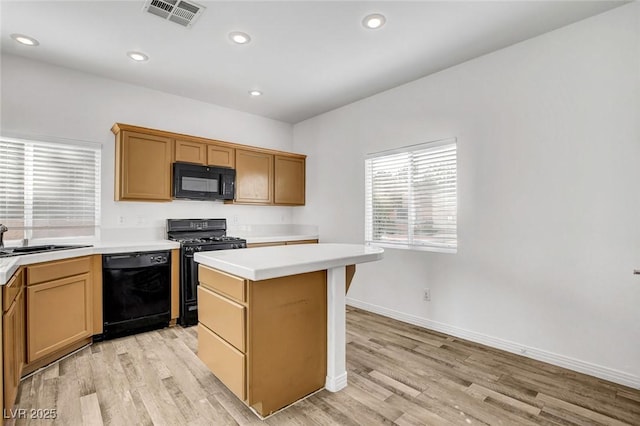 kitchen with light hardwood / wood-style flooring, sink, a kitchen island, and black appliances