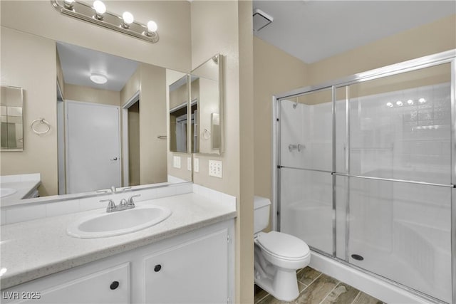 bathroom with hardwood / wood-style flooring, vanity, toilet, and a shower with shower door