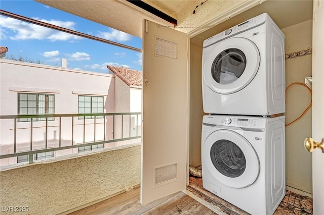 laundry room with wood-type flooring and stacked washing maching and dryer