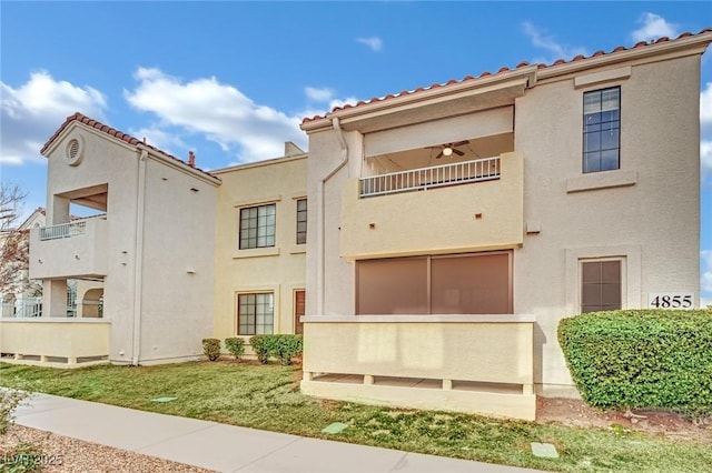 view of front of house with a front yard, a balcony, and ceiling fan