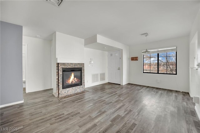 unfurnished living room with a tiled fireplace and light hardwood / wood-style floors