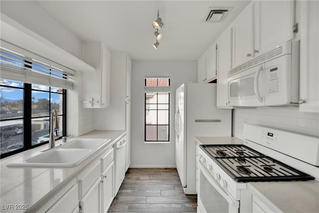 kitchen with white cabinetry, sink, backsplash, a healthy amount of sunlight, and white appliances