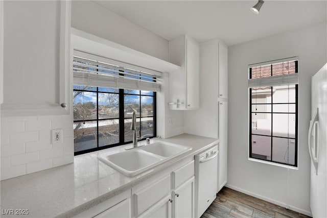 kitchen with white cabinetry, sink, light stone counters, light hardwood / wood-style floors, and white appliances