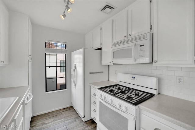 kitchen featuring rail lighting, white cabinets, decorative backsplash, light hardwood / wood-style floors, and white appliances