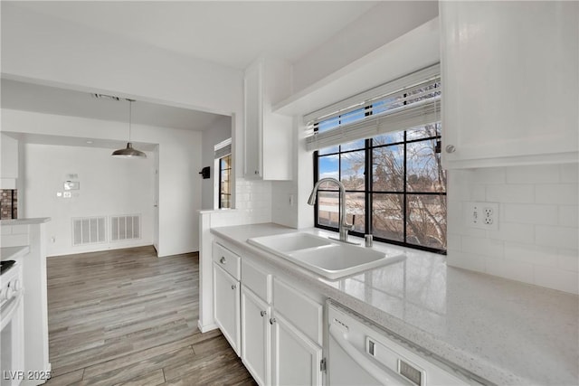 kitchen featuring dark hardwood / wood-style floors, white cabinetry, sink, hanging light fixtures, and light stone counters