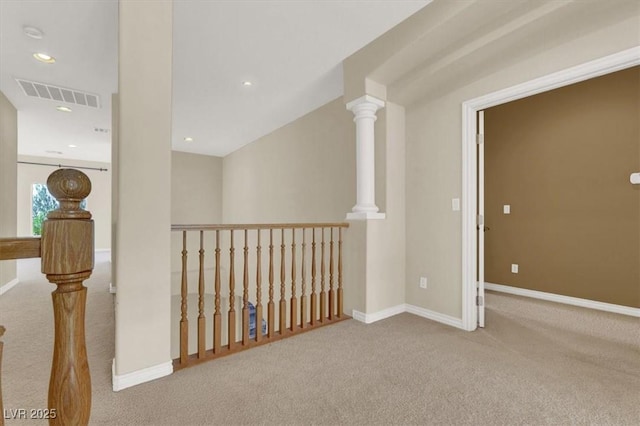 hall featuring light colored carpet and decorative columns