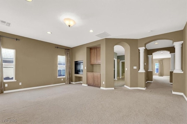 unfurnished living room featuring light colored carpet and ornate columns