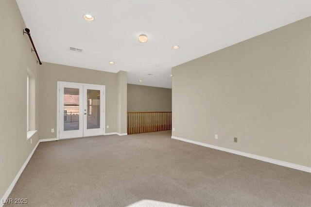 spare room featuring light carpet and french doors