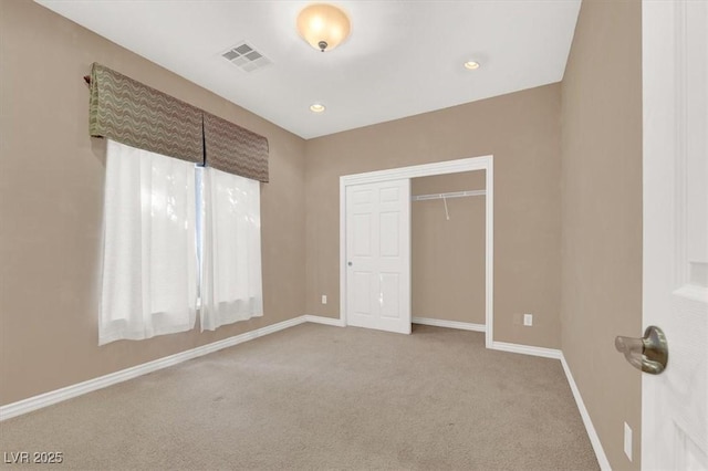 unfurnished bedroom with light colored carpet and a closet