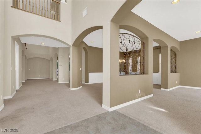 hallway featuring light carpet and a high ceiling