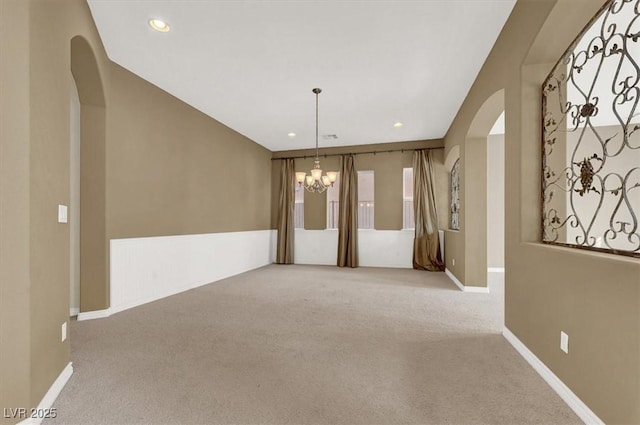 unfurnished room with light carpet and a chandelier