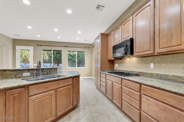 kitchen with light tile patterned flooring, sink, tasteful backsplash, stainless steel gas stovetop, and light stone countertops