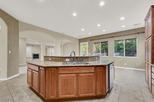 kitchen with light stone countertops, sink, and a center island with sink