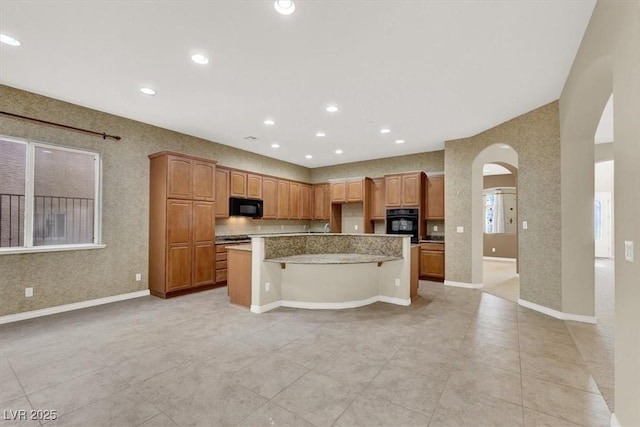 kitchen with light stone counters, a kitchen breakfast bar, and a kitchen island