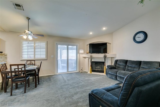 living room with lofted ceiling, a tile fireplace, ceiling fan, and carpet