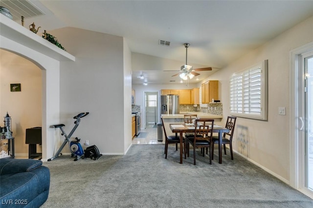 carpeted dining room with ceiling fan and vaulted ceiling