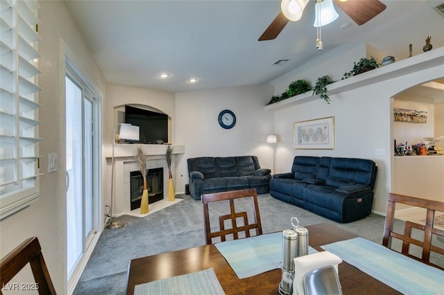 living room with a tile fireplace, carpet floors, and ceiling fan