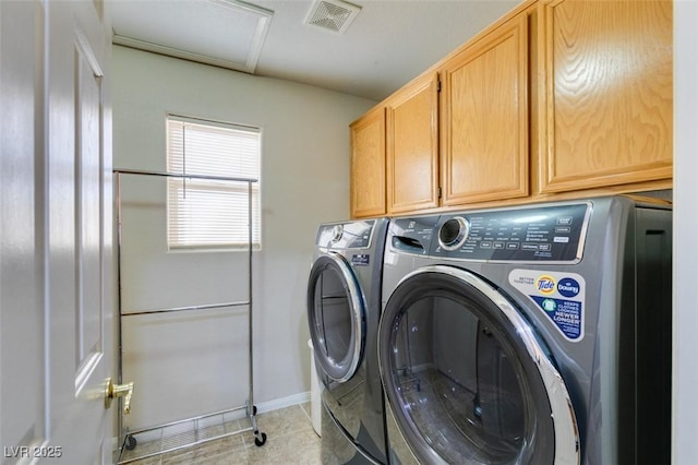 clothes washing area featuring cabinets, light tile patterned floors, and washing machine and clothes dryer