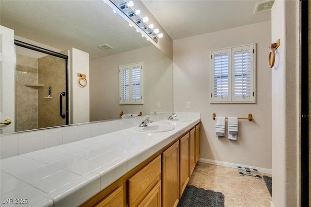 bathroom with a shower with door, vanity, and tile patterned floors