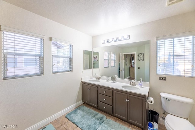 bathroom featuring tile patterned flooring, vanity, a healthy amount of sunlight, and toilet